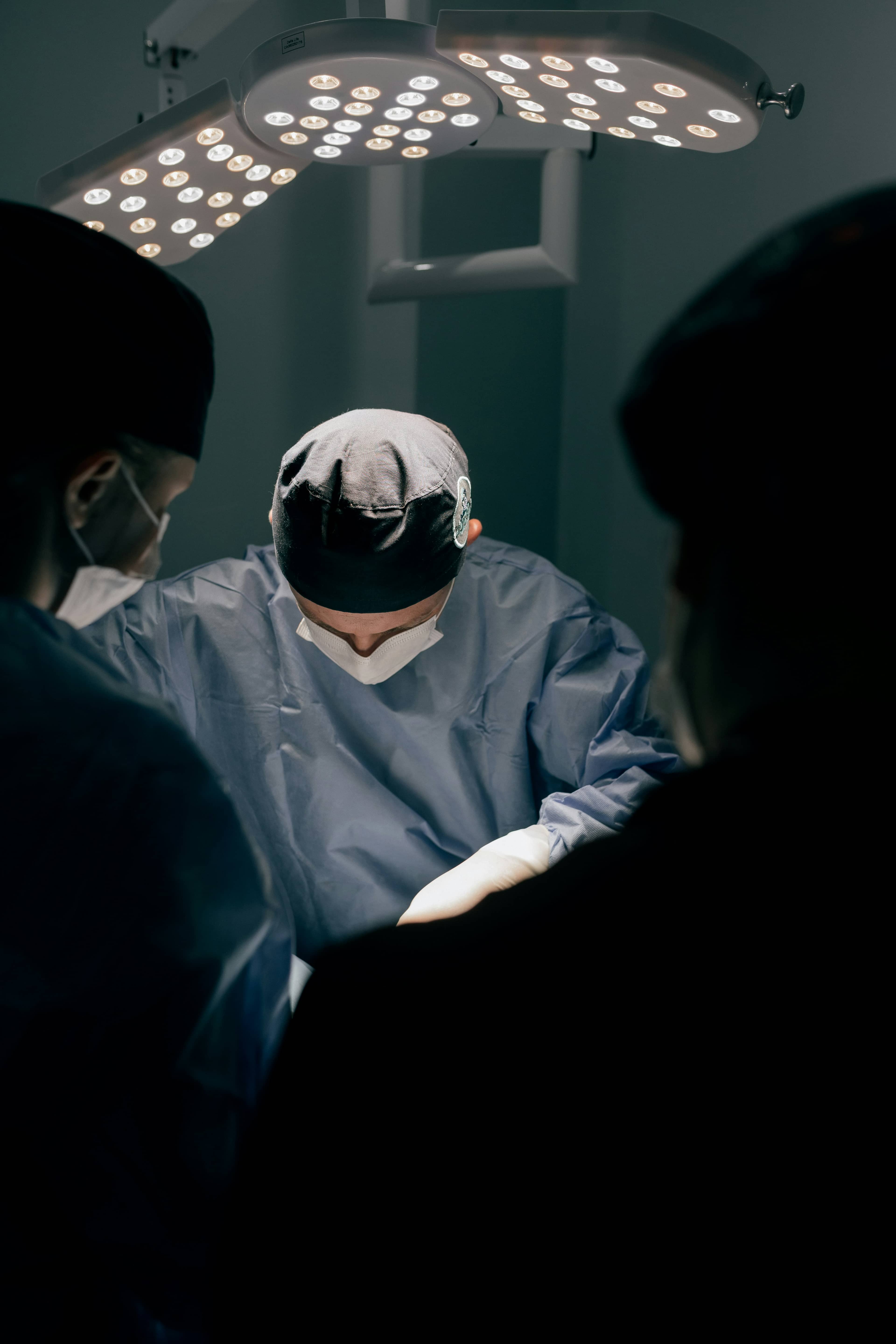 Cirurgião veterinário opera sob a luz do foco cirúrgico, cercado pela equipe